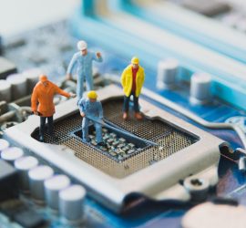 Four model crewmen working on a CPU port on a motherboard