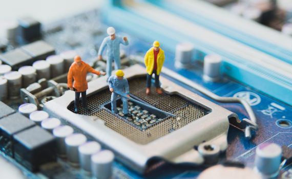 Four model crewmen working on a CPU port on a motherboard