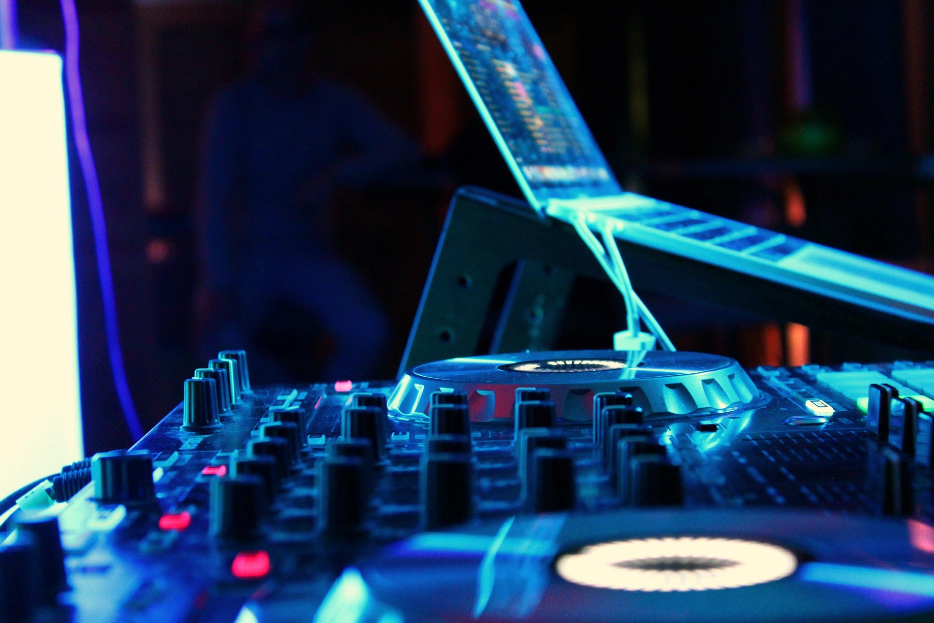 A shot accross the top of some DJ decks with a laptop on a stand positioned next to the decks.